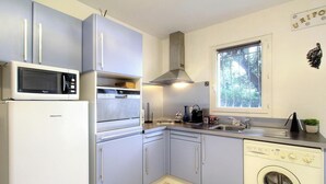 Ett kompakt kök med ett Hisense-kylskåp, en mikrovågsugn, en spis, en diskho och en tvättmaskin.