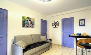 Ein Zimmer mit einer Couch, einem Esstisch mit Stühlen und zwei Türen.
