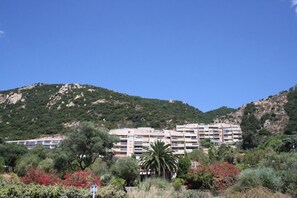 Ein mehrstöckiges Hotel mit Balkonen, umgeben von viel Grün und Hügeln.