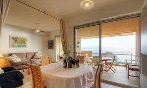 Ein Zimmer mit Balkon, Esstisch und einer Couch.