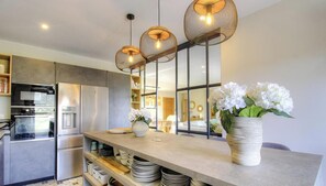 Una cocina moderna con una isla central, electrodomésticos de acero inoxidable y un florero con flores blancas.
