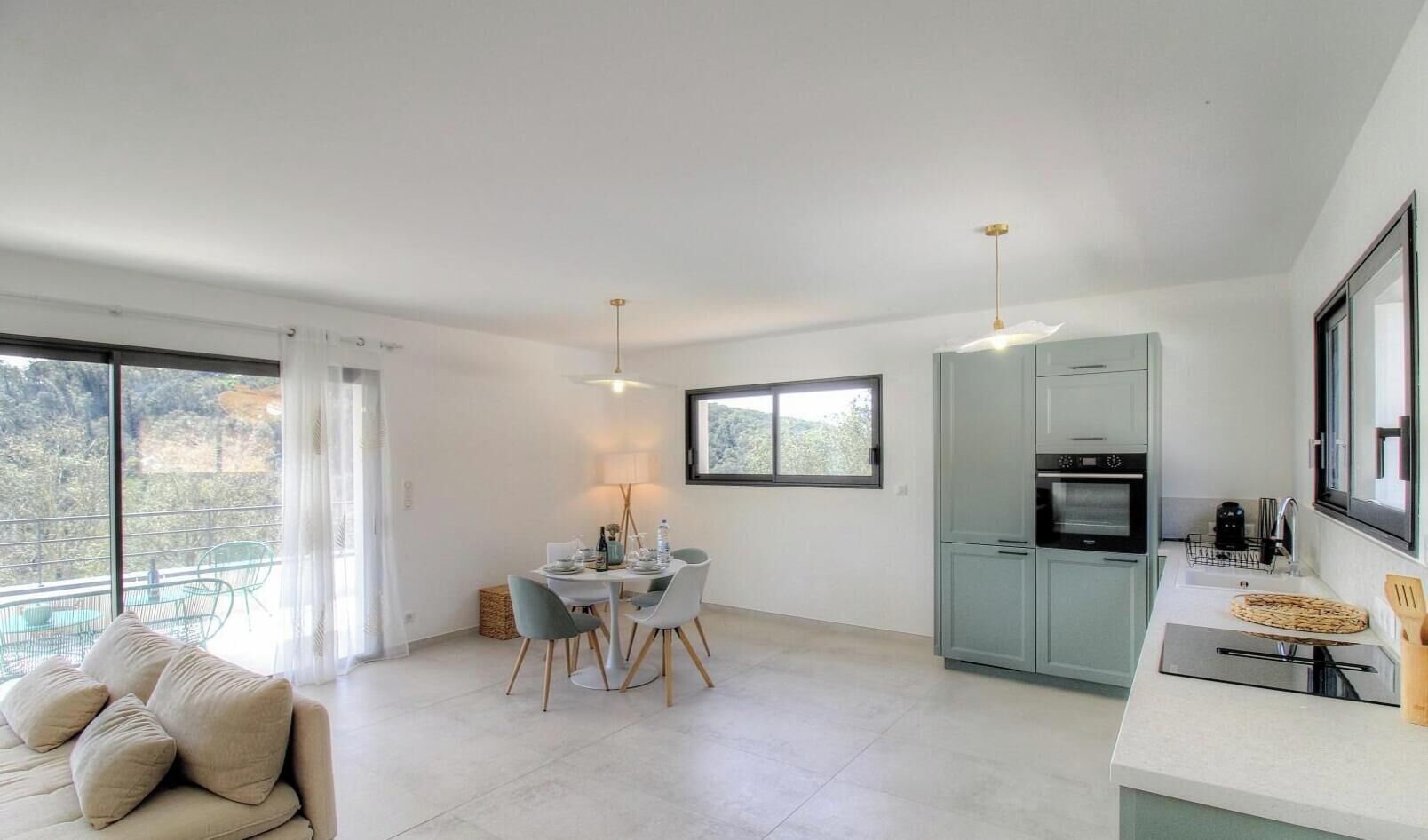 Eine moderne Küche mit Essbereich, großen Fenstern und einem Balkon.