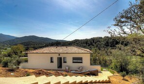 A single-story house with a tiled roof, a small porch, and a view of a hilly landscape. - Casa Valinina 1 - BASTELICACCIA (BASTELICACCIA)