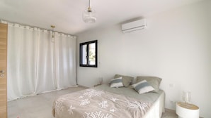 Une chambre à coucher avec un lit, des rideaux, une fenêtre, un climatiseur et une table de chevet.