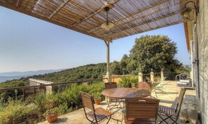 A covered outdoor seating area with a table and chairs, overlooking a mountainous landscape. - Paulina1 - OLMETO - B&B (OLMETO)