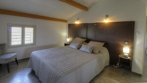 Une chambre à coucher avec un lit, deux lampes de chevet, une fenêtre et une chaise.