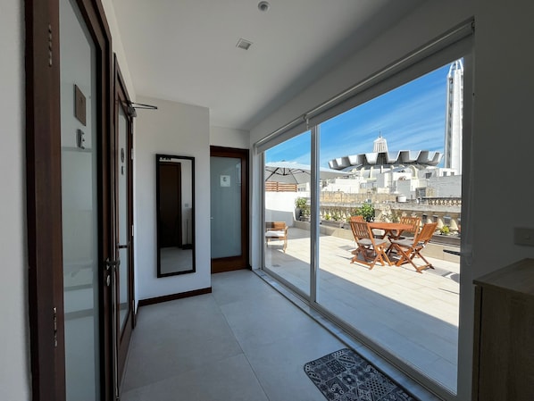 Un appartement moderne doté d’une grande porte-fenêtre coulissante donnant sur un balcon avec vue sur la ville.