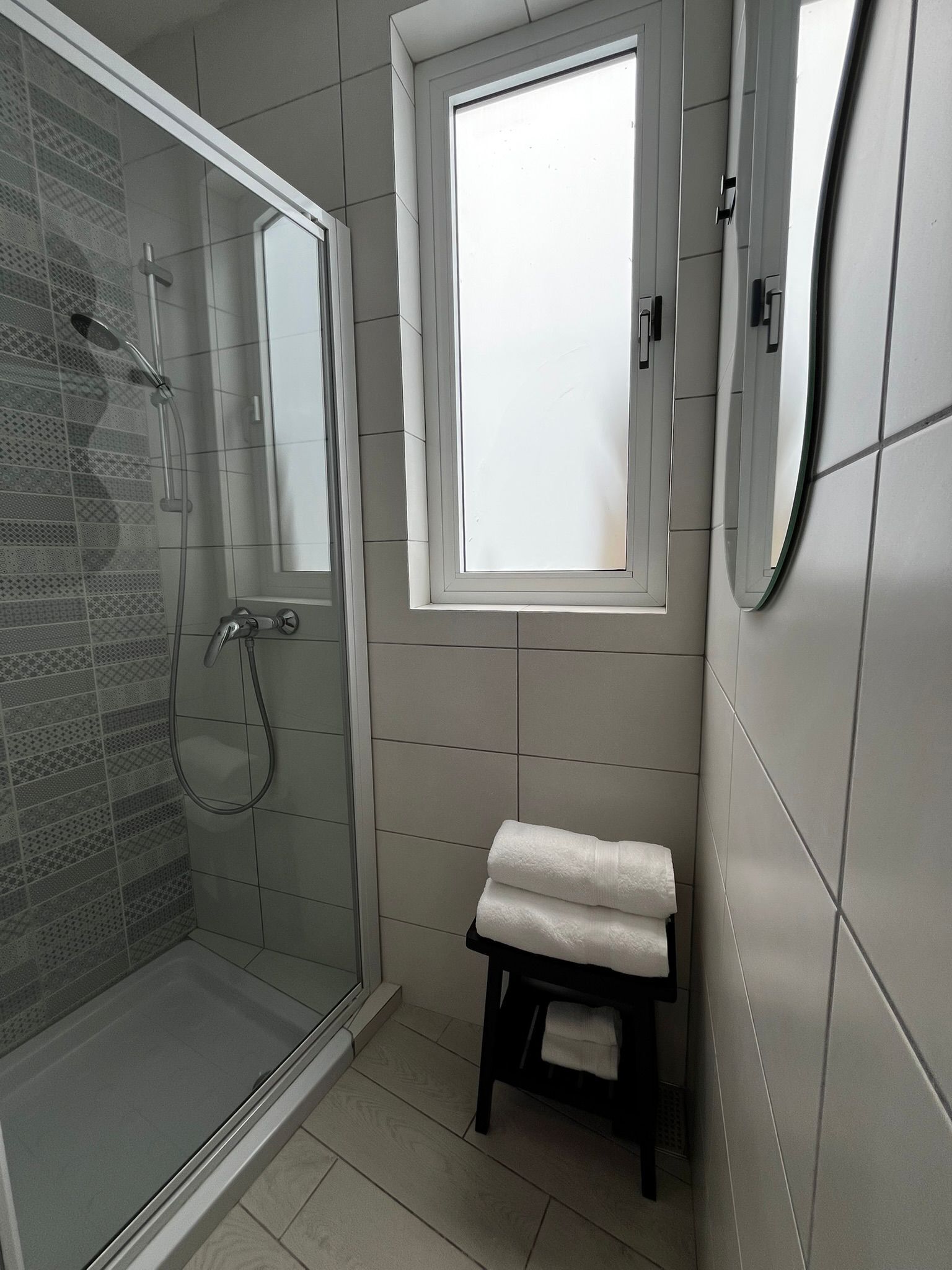 Un bagno moderno con box doccia in vetro, una piccola finestra e un portasciugamani.