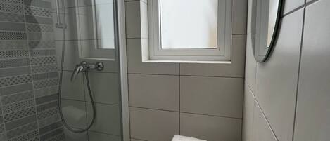 Un bagno moderno con box doccia in vetro, una piccola finestra e un portasciugamani.