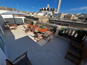 A rooftop terrace with wooden furniture and a view of the cityscape.