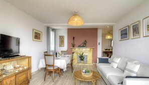 A living room with a TV, dining table, chairs, a sofa, a fireplace, and a TV stand. - Cours Napoleon - AJACCIO (AJACCIO)