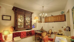 Un comedor con un aparador de madera, una araña y una mesa con sillas.