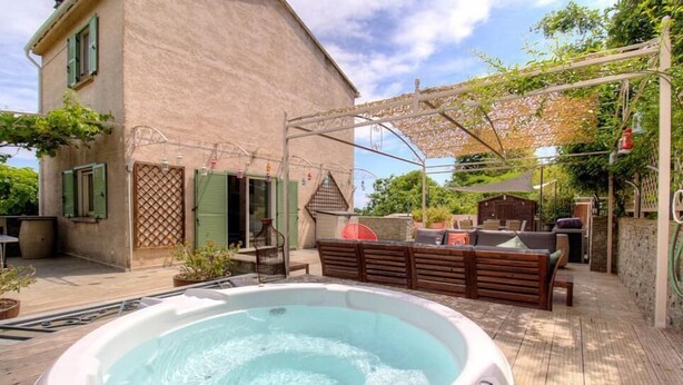 Un jacuzzi, asientos exteriores y una pérgola en una terraza de madera.