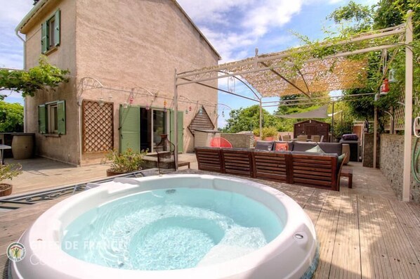 A hot tub, outdoor seating, and a pergola on a wooden deck. - A casa sopra - TALASANI (TALASANI)