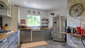 Una cocina moderna con electrodomésticos de acero inoxidable, un ventanal y una pared de piedra.
