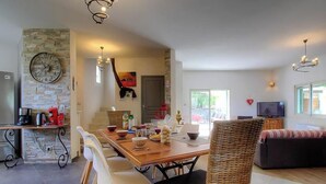 Amplia sala de estar con mesa de comedor, sillas, sofá y televisor.