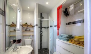 Ein modernes Badezimmer mit Duschkabine aus Glas, einem weißen Waschbecken und ordentlich gefalteten Handtüchern.