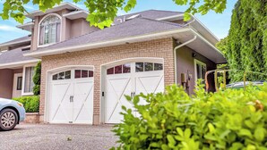 Une maison à deux étages avec un garage, une grande fenêtre et une pelouse bien entretenue.