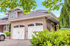 A two-story house with a garage, a large window, and a well-maintained lawn. - 2BR Surrey Pool Suite Near White Rock (Surrey)