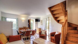 Amplia sala de estar con una mesa de comedor, varias sillas, un sofá y una escalera de madera.