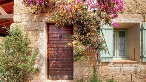 Un edificio rústico de piedra con puerta de madera y ventana con persianas.