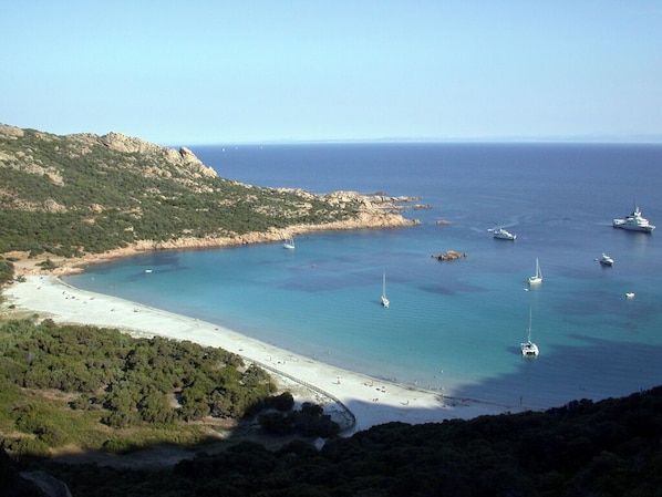 Eine Küstenlandschaft mit Strand, Booten und klarem, blauem Wasser.