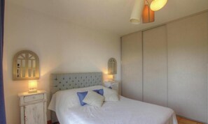 Un dormitorio con cama, lámparas de noche, armario y espejo.