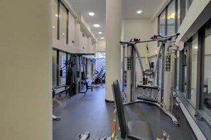 A gym with various exercise equipment, large windows, and a clean, modern design.