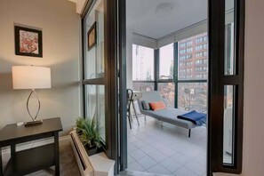 A modern room with a bed, a table, a lamp, and a large window.