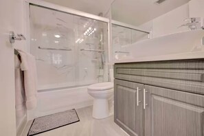 Une salle de bain moderne avec une douche à parois de verre, des toilettes et un meuble-lavabo avec des placards.