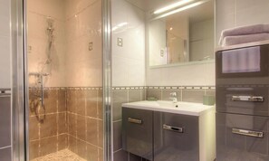 Un bany amb plat de dutxa de vidre, un lavabo i un mirall sobre el lavabo.