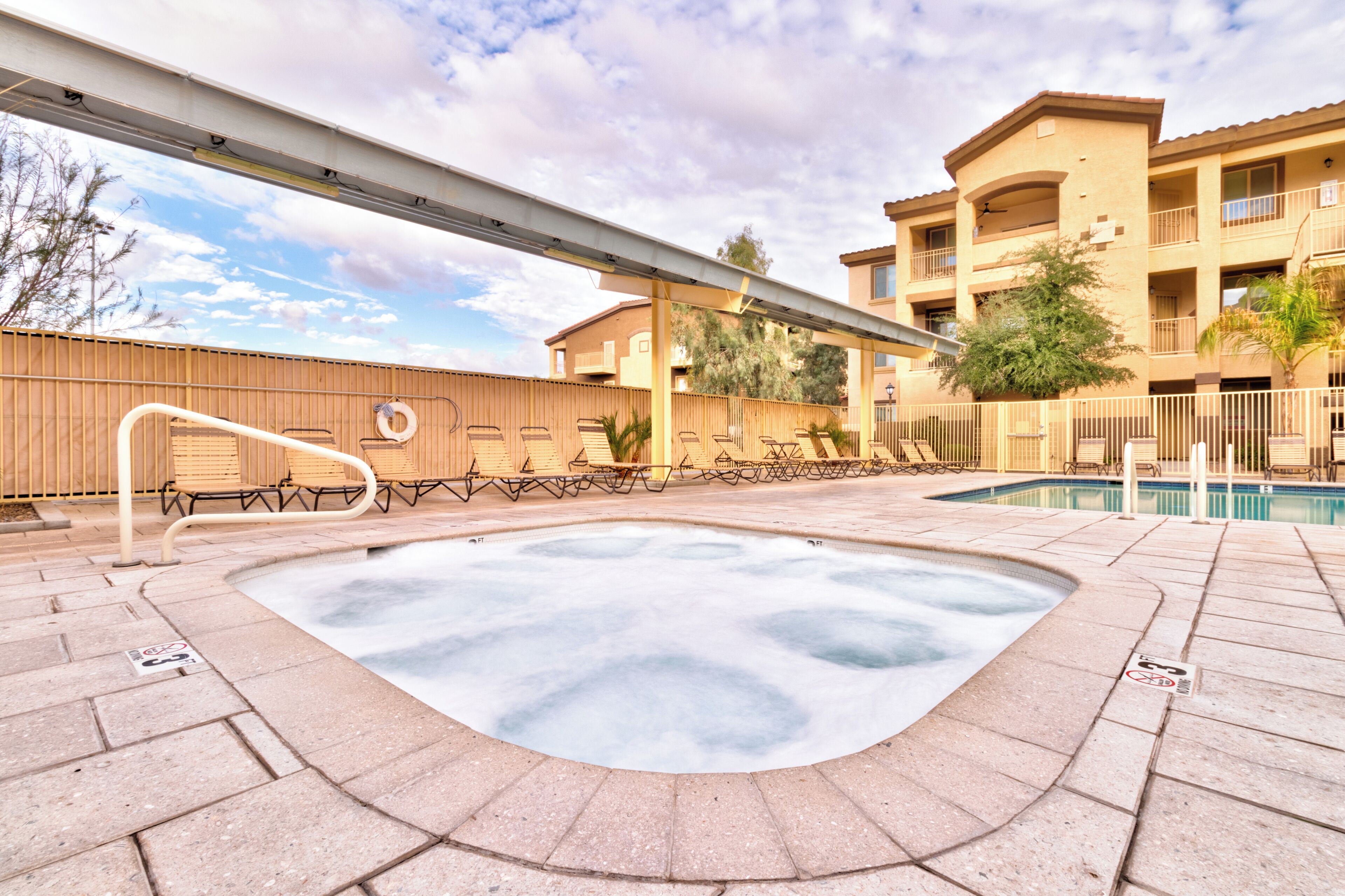 A hot tub area with a pool, outdoor seating, and a covered patio.