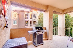 Ein Balkon im Freien mit einem Grill, einem Metalltisch und Blick auf ein Gebäude mit Balkonen.