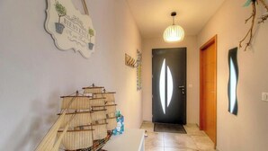 Een gang met een model schip, een welkomstbord, een deur en een hanglamp.