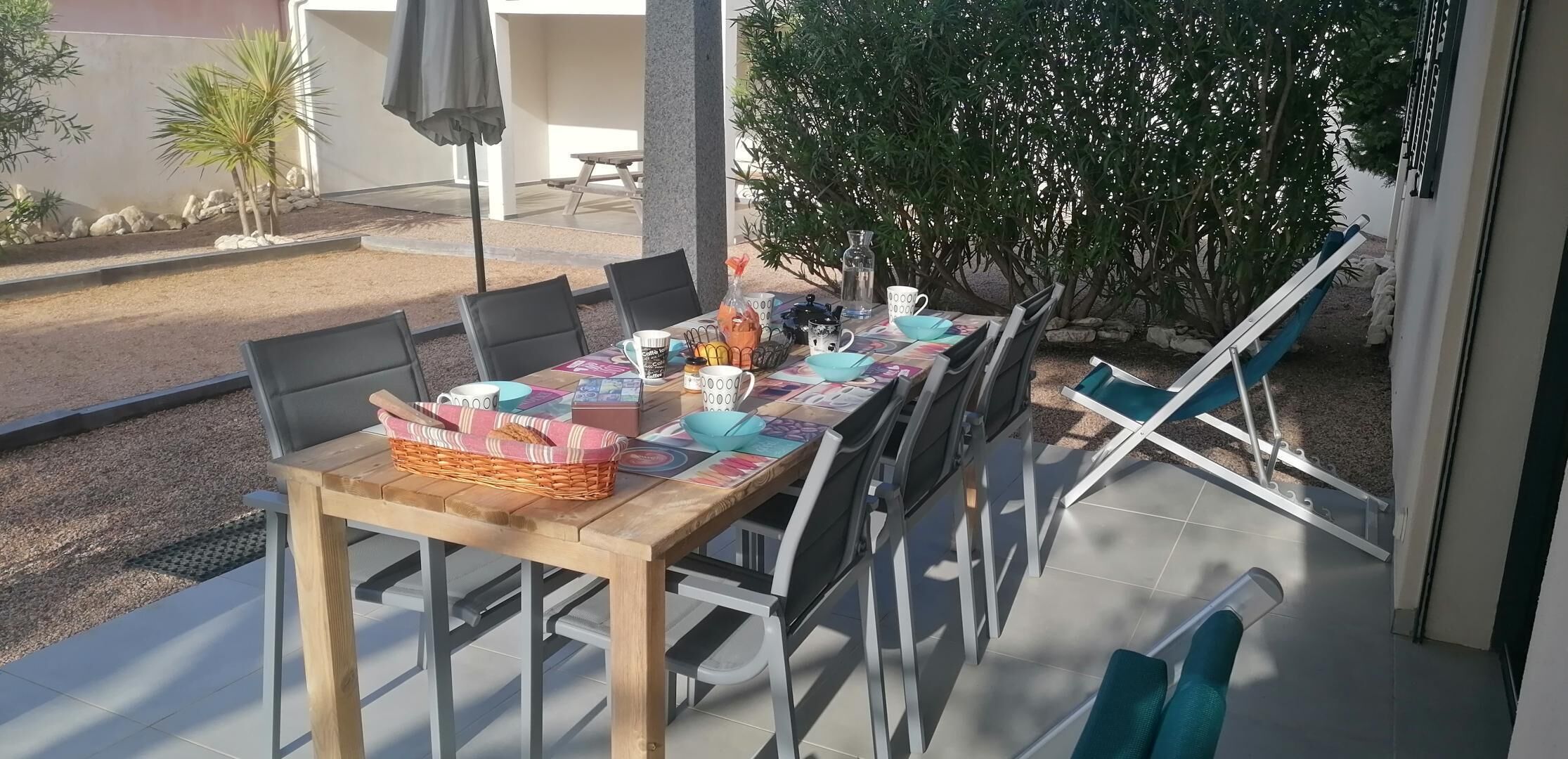 An outdoor dining area with a long table, chairs, and a bench.
