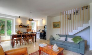 Ein geräumiger Wohnbereich mit Esstisch, Sofa und Wendeltreppe.