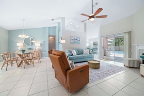 A spacious living area with a massage chair, a dining table, and a blue sofa.