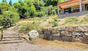 Una escalera de piedra que sube, un muro de piedra y un edificio con techo rojo.