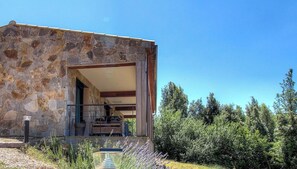 Un edificio de piedra con balcón, cielo despejado y vegetación circundante.