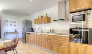 Una cocina moderna con armarios de madera, electrodomésticos de acero inoxidable y un comedor con mesa y sillas.