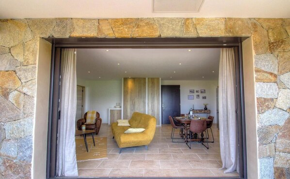 Una habitación con pared de piedra, un sofá, una mesa de comedor y sillas.