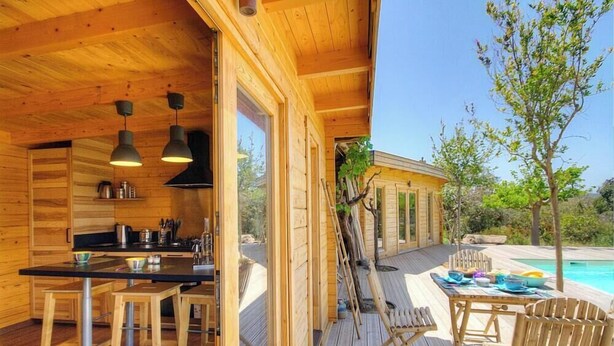 Una cabaña de madera con cocina, comedor y piscina.