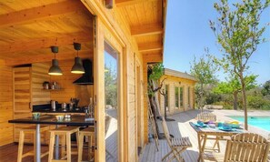 Una cabaña de madera con cocina, comedor y piscina.