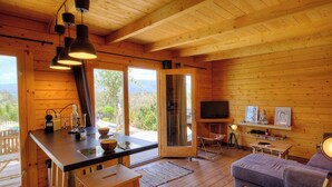 Interior de una cabaña de madera con cocina, mesa de comedor y asientos.