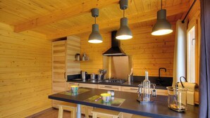 Un interior de madera con una cocina que incluye estufa, armarios e iluminación colgante.