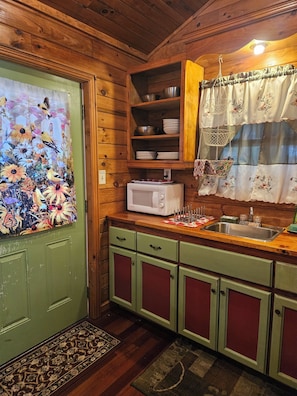 A kitchen with wooden cabinets, a microwave, and a sink. - Adorable 1-bedroom cabin with AC in welcoming Bryson City (Bryson City)