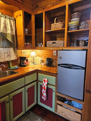 A kitchen with wooden cabinets, a refrigerator, a sink, and various kitchen appliances. - Adorable 1-bedroom cabin with AC in welcoming Bryson City (Bryson City)