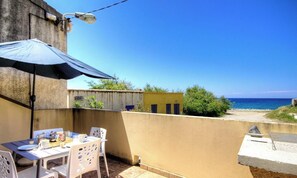 A patio with a table and chairs, a blue umbrella, and a view of the sea. - Mare e Torre - FARINOLE (FARINOLE)