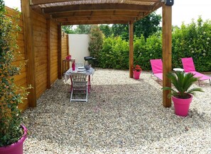 A covered patio area with a table and chairs, surrounded by potted plants and a gravel ground. - Ermiccia - PATRIMONIO (PATRIMONIO)