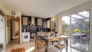 Eine moderne Küche mit Essbereich, großen Fenstern und Blick ins Freie.